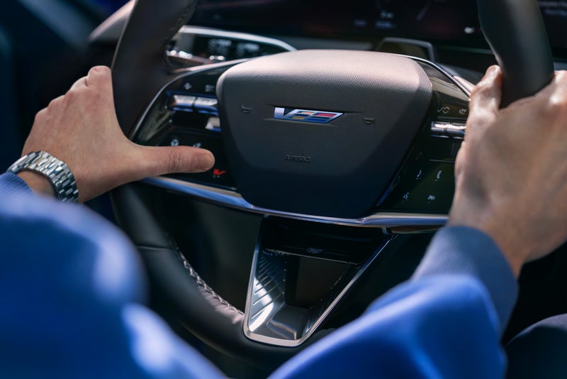 Close-up of a Man About to Press the V-Button on the 2026 OPTIQ-V Steering Wheel | Bill Dodge Cadillac in Westbrook ME