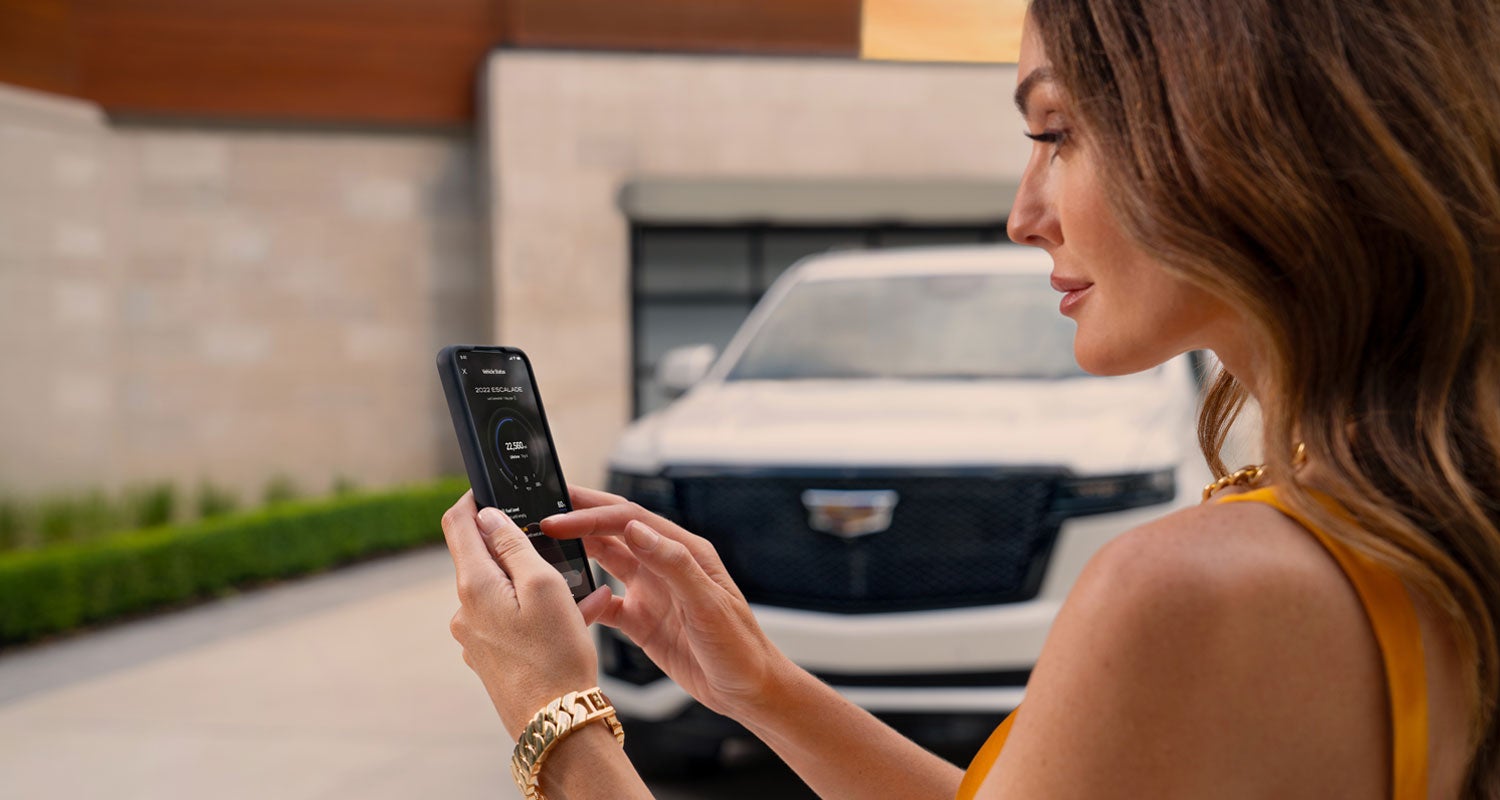 lady checking her mobile with a Cadillac vehicle background | Bill Dodge Cadillac in Westbrook ME